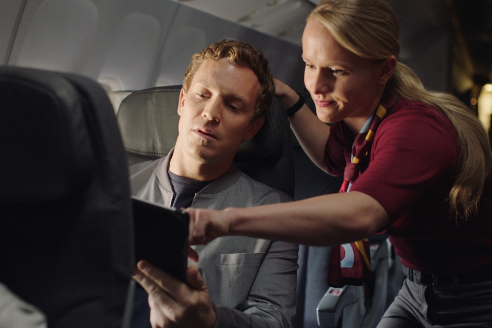 A couple sitting in Rouge seating using the in-flight system player aboard an Air Canada Rouge flight.